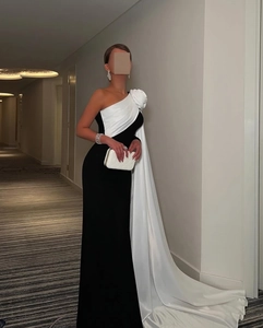 Detail van elegante avondjurk met één schouder, wit bloemaccent en zwart lijfje