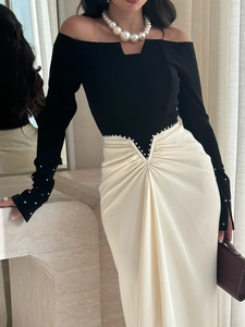 Detail van de zwart-witte off-shoulder jurk met elegante parelversieringen erop