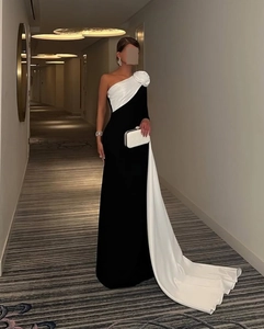 Detail van zwarte jurk met oversized witte 3D-roos op de schouder en een elegante cape