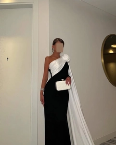 Detail van elegante one-shoulder avondjurk met grote witte zijden bloem en zwart lijfje