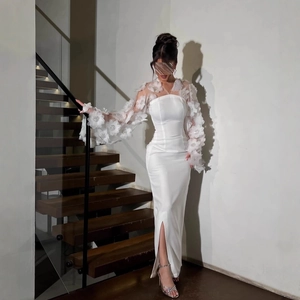 Elegante witte avondjurk met transparante bloemenmouwen en een hoge zijsplit
