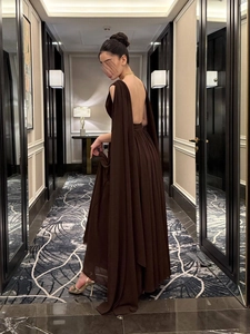 Detail van elegante open rug donkerbruine chiffon avondjurk met zwierige cape mouwen