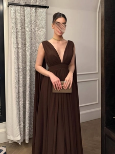Detail van elegante donkerbruine chiffon jurk met V-hals en stijlvol gedrapeerd cape-ontwerp