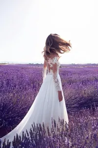 Robe de mariée élégante en dentelle à manches longues avec dos nu dans un champ de lavande