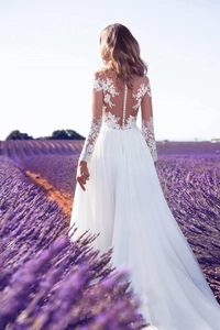 Robe de mariée élégante en dentelle à manches longues avec dos nu dans un champ de lavande