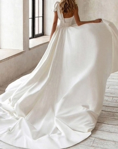 Elegant back view of white satin wedding dress with long train and bow detail