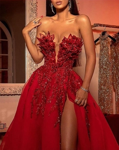 Detail of red sequined off-shoulder gown featuring 3D floral petals and thigh-high slit