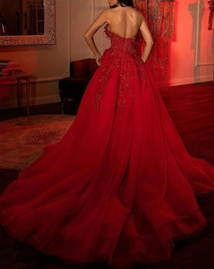 Detail of red off-shoulder gown featuring intricate sequin embroidery and layered mesh