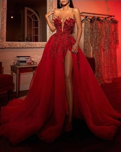 Exquisite close-up of red sequin embroidery and sheer mesh slit on luxury evening gown