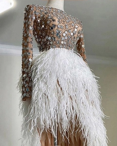 Dettaglio di paillettes luccicanti e piume bianche su un elegante abito da sera