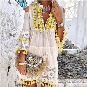 Détail de robe bohème blanche avec des pompons brodés jaunes et de la dentelle