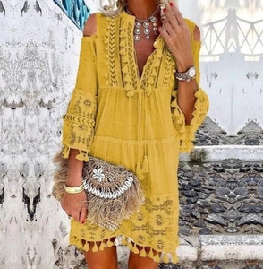 Détail de robe bohème jaune avec dentelle blanche et pompons sous une lumière d'été