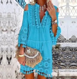Détail de robe bohème bleue à épaules dénudées avec pompons et empiècement dentelle