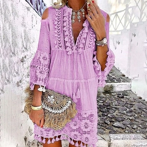 Détail d'une robe bohème lilas avec broderie en dentelle, col en V et ourlet à pompons