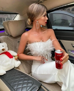 Detail view of stylish white feather bandeau jumpsuit top worn by a model in luxury car