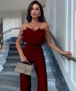 Detail of burgundy tube top with feather trim and high-waisted wide-leg trousers