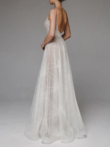 Detailed close-up of white evening dress featuring geometric embroidery and sheer texture