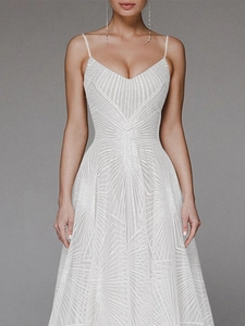 Detailed view of white V-neck evening gown with geometric sequin patterns and thin straps