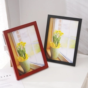 Minimalist red and black wooden photo frames showcasing floral prints on a white table