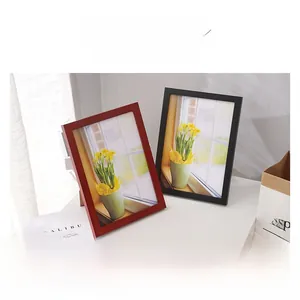 Detail view of stylish red and black wooden frames with floral photography on a desk