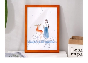 Detail of an orange pine wood frame featuring a girl and deer illustration on a desk