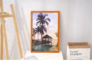 Detail of pine wood frame with tropical beach art standing on a desk with natural lighting