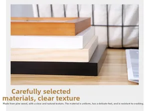 Close-up of stacked pine wood frames in natural, white, and black finishes with fine texture
