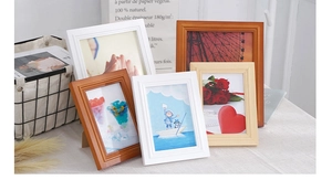 Collection of wooden picture frames in white, oak, and walnut finishes on a desk