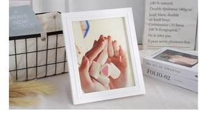 Detail of white Nordic solid wood photo frame with warm lifestyle decor and textures