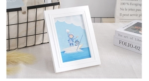 Detail of a white Nordic solid wood photo frame with tiered edges and cartoon illustration