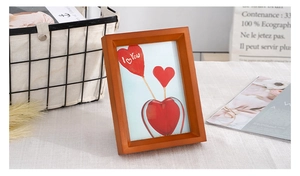 Close-up of a cherry wood frame with a heart-themed art print on a stylish desk