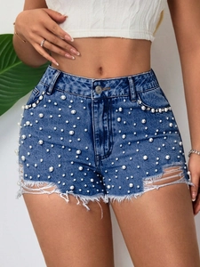 Dettaglio degli shorts in denim blu a vita alta con perle bianche e orli sfrangiati