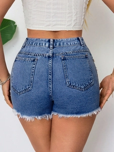 Dettaglio degli shorts in denim blu a vita alta con orlo a frange e accenti di perle