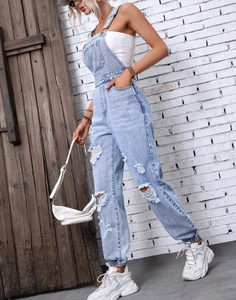 Close-up of light blue distressed denim overalls with adjustable straps and ripped details