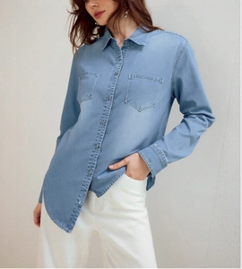 Close-up of light blue denim shirt showing front pockets and button-down collar texture