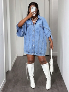 Detail of loose fit denim shirt dress featuring flap pockets and metallic buttons