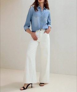 Detail of light wash denim shirt paired with white wide-leg trousers for a casual office look