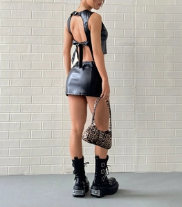 Detalle de conjunto de dos piezas en cuero sintético negro con top y minifalda
