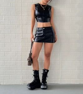Detalle de conjunto de dos piezas en piel sintética negra con crop top y minifalda