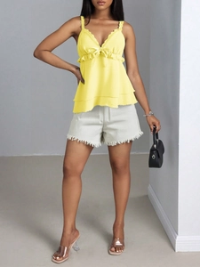 Détail du caraco jaune avec volants en dentelle, nœud et short en jean avec franges