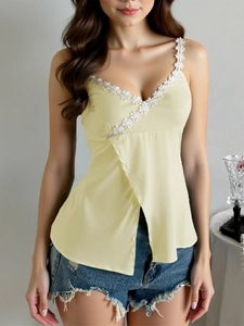 Detail of light yellow V-neck camisole with white floral lace trim and wrap design style