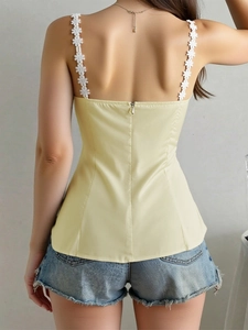Detail of floral lace straps and back zipper on a slim fit pale yellow camisole top