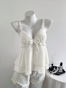 Détail du caraco en mousseline blanche avec nœud en dentelle et ourlet à volants étagés