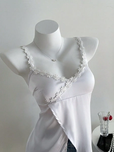 Detail of white satin camisole featuring delicate floral lace trim and V-neckline finish