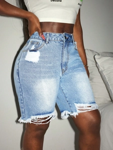 Detail of light blue high-waisted distressed denim shorts with frayed hems and ripped texture