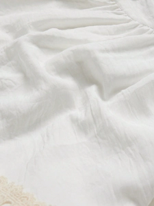 White vintage lace puff sleeve dress showing textured cotton fabric and crochet details