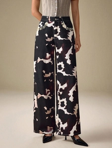Détail de jean taille haute à jambe large avec bordure en perles et motif vache