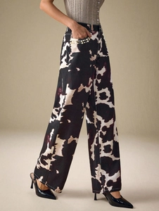 Gros plan sur les perles et l'imprimé vache de ce pantalon large en denim