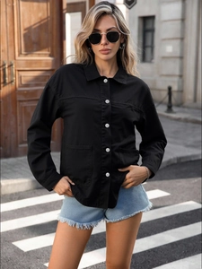 Close-up of black denim jacket with silver buttons and large cargo pockets on street
