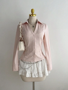 Detail of light pink long-sleeved shirt with vertical pleats and translucent buttons